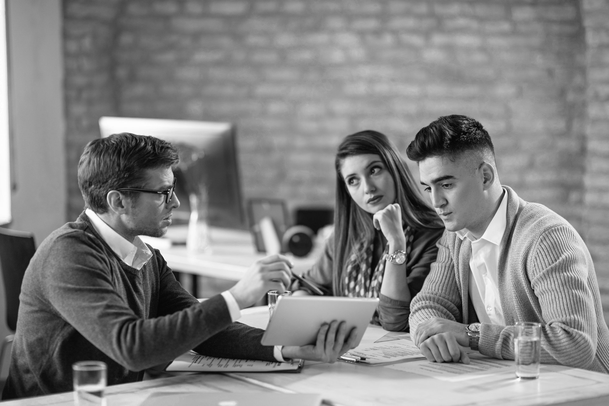 young-couple-using-digital-tablet-with-their-insurance-agent-consultations-officeByN